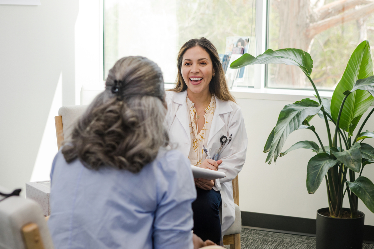 A PMHNP speaks with a patient in their office.