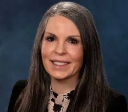 Regina Prosser smiling, dark background